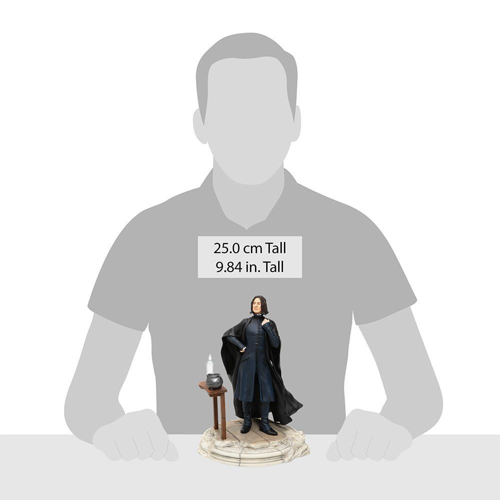 Severus Snape-beeldje, 25 cm hoog, staand met een tafel en kaars, grijze mantel, op een witte sokkel.