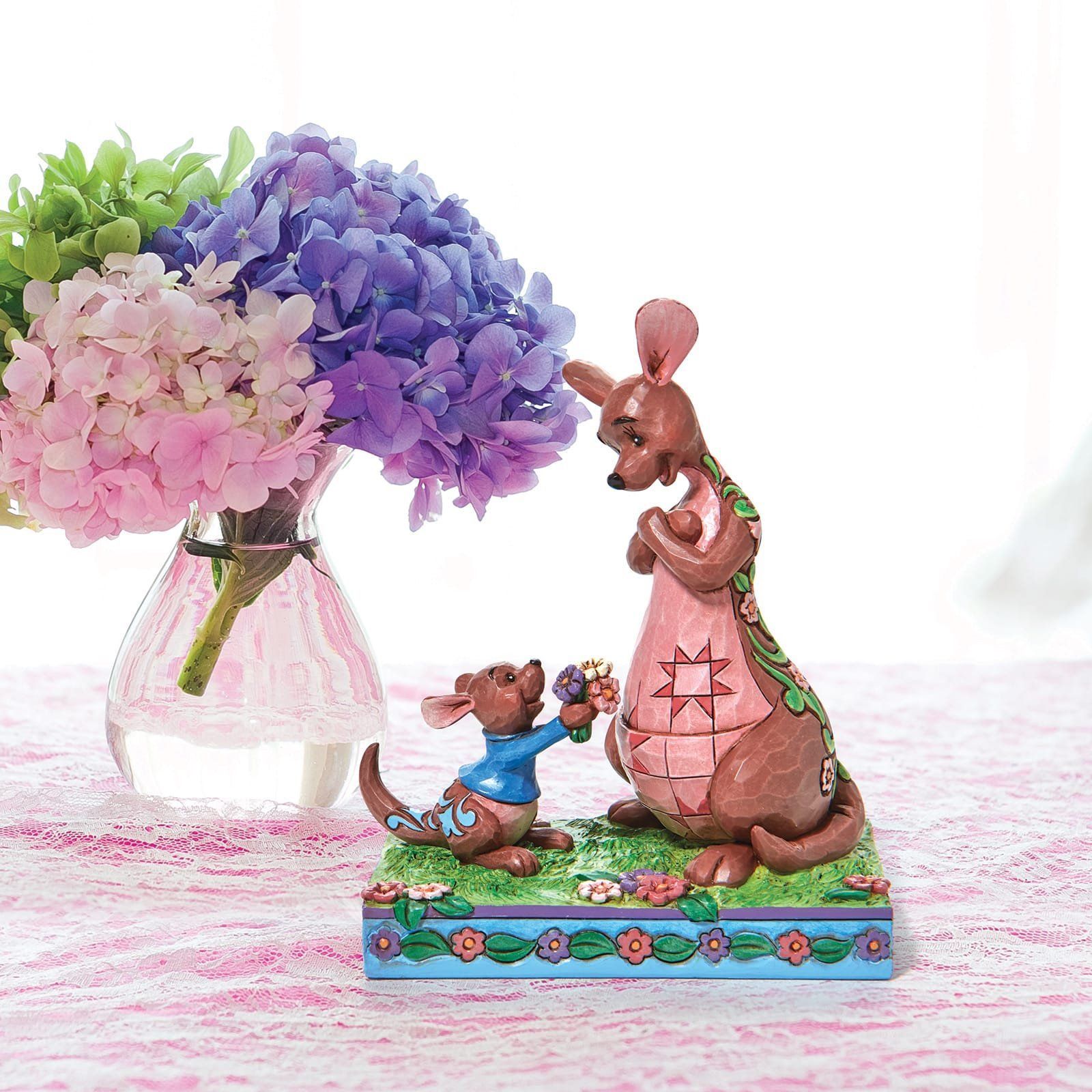 Kangoeroefiguurtje: een jong kangoeroetje biedt bloemen aan een grotere kangoeroe. Links staan hortensia's in een vaas.