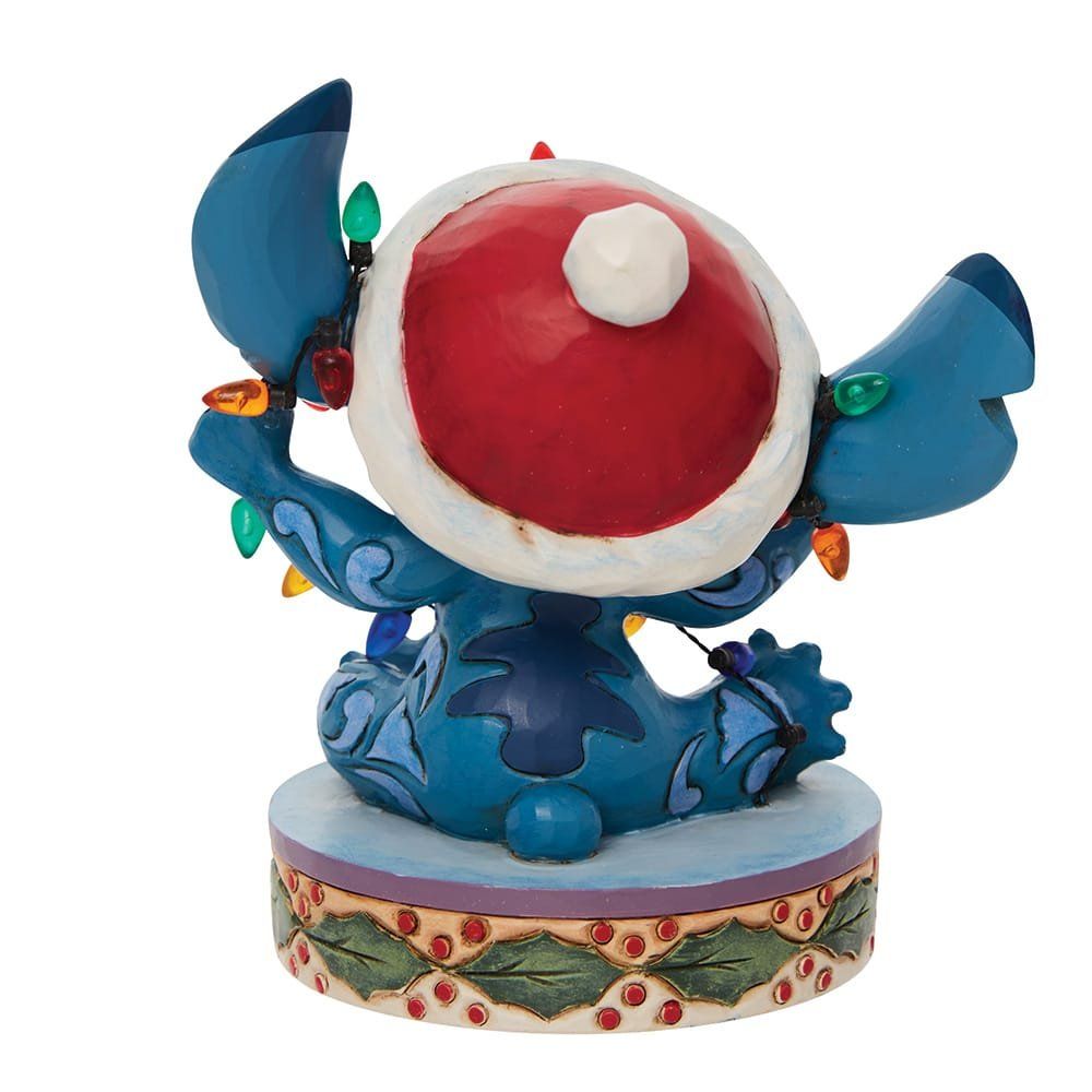 Een Stitch-figuurtje verstrikt in kerstverlichting, met een kerstmuts op.