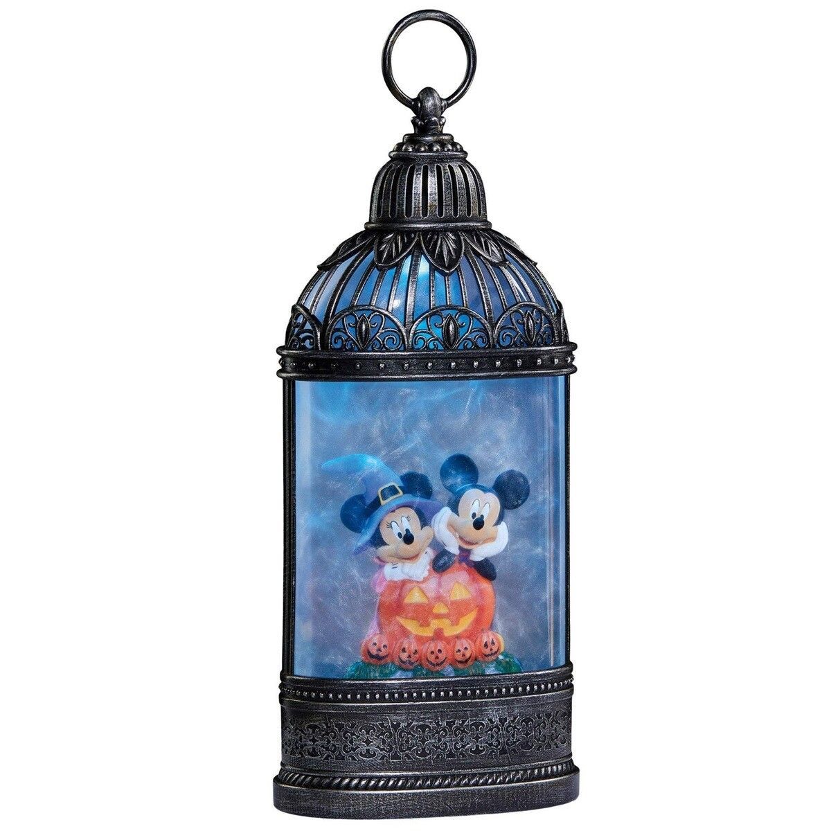 Een Halloweenlantaarn met Mickey en Minnie Mouse en een paarse gloed, op een tafel voor een paarse bank.