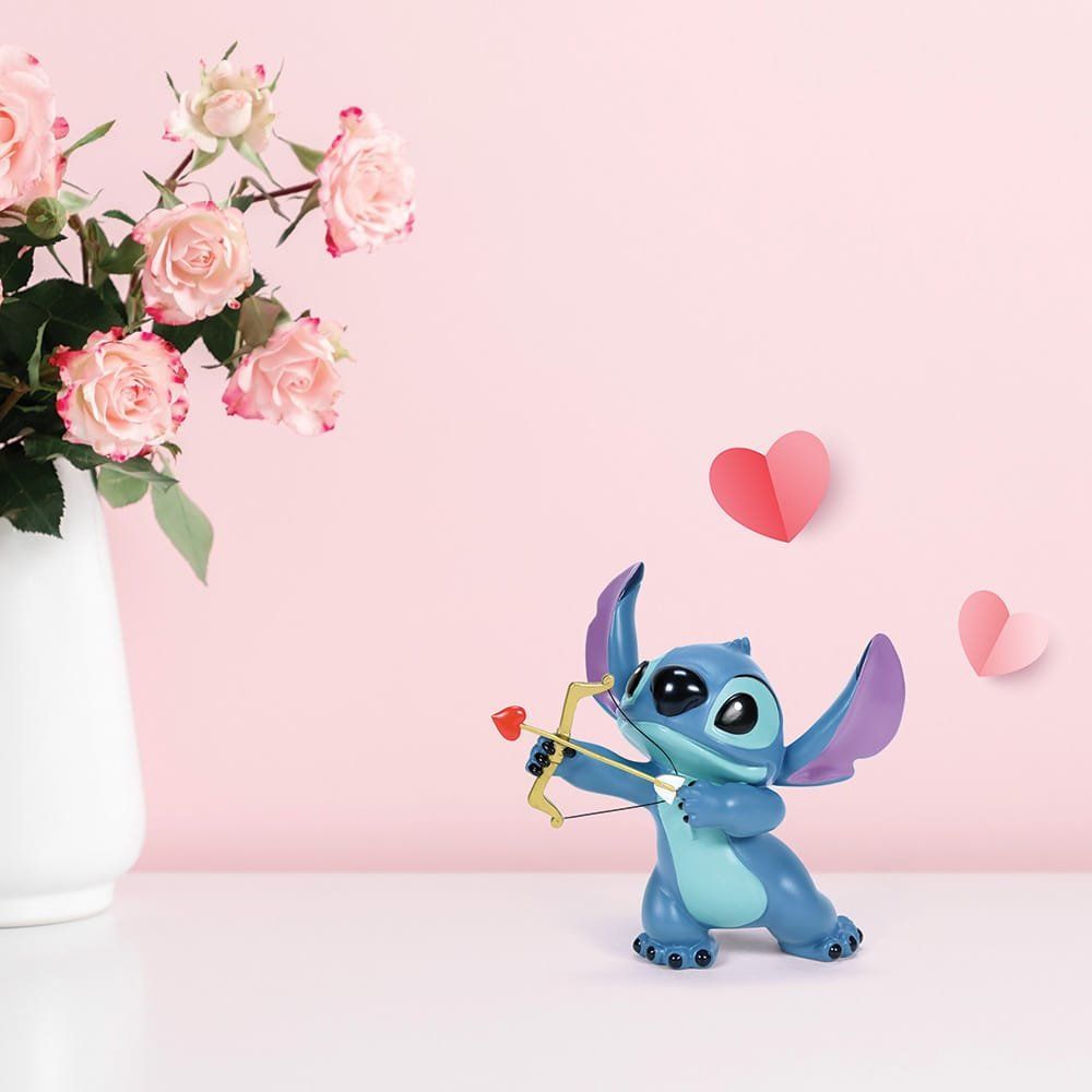 Stitch stelt Cupido voor met een pijl en boog, roze rozen in een vaas en roze hartjes op een roze achtergrond.