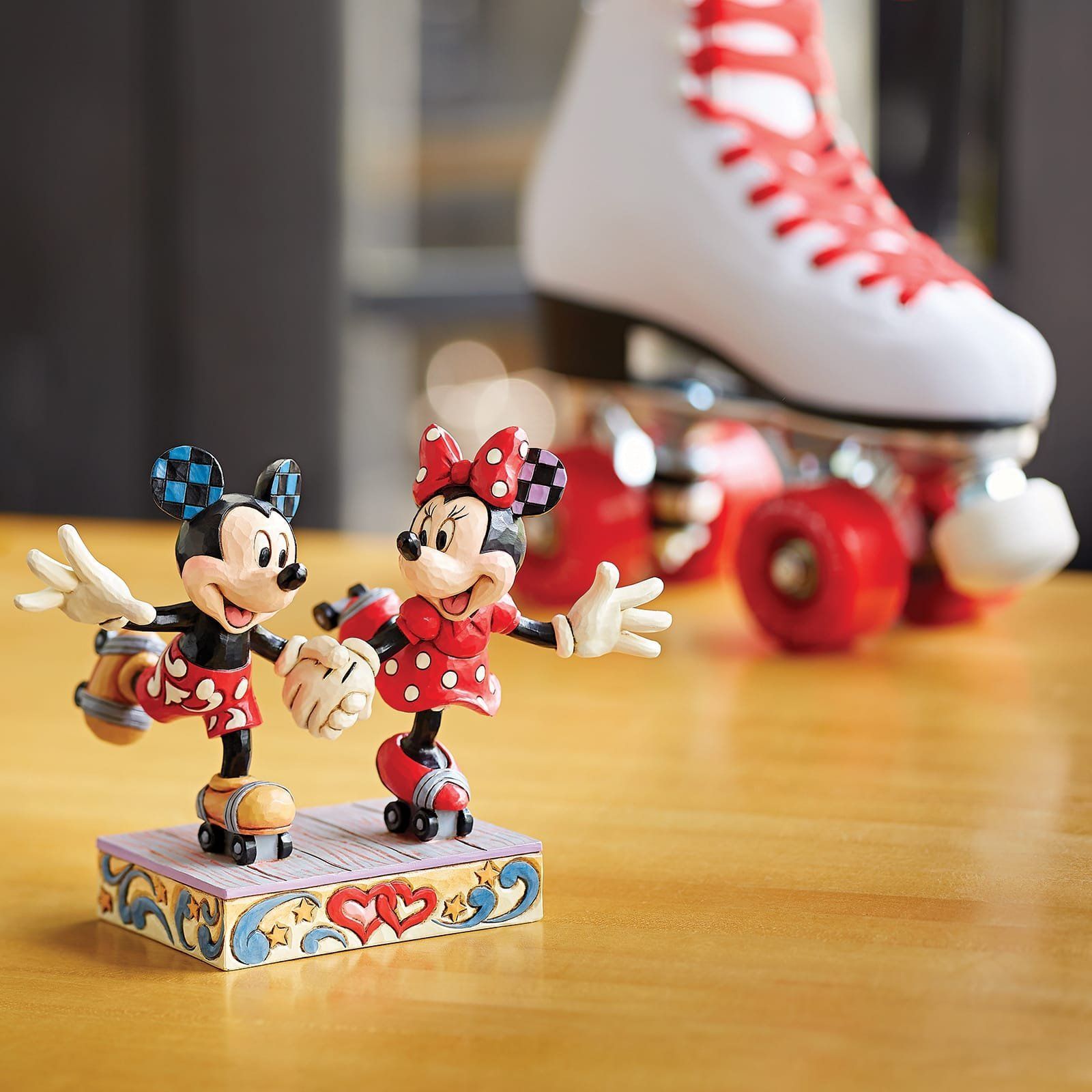 Mickey en Minnie Mouse-figuurtjes op rolschaatsen, met op de achtergrond een paar rode en witte rolschaatsen.