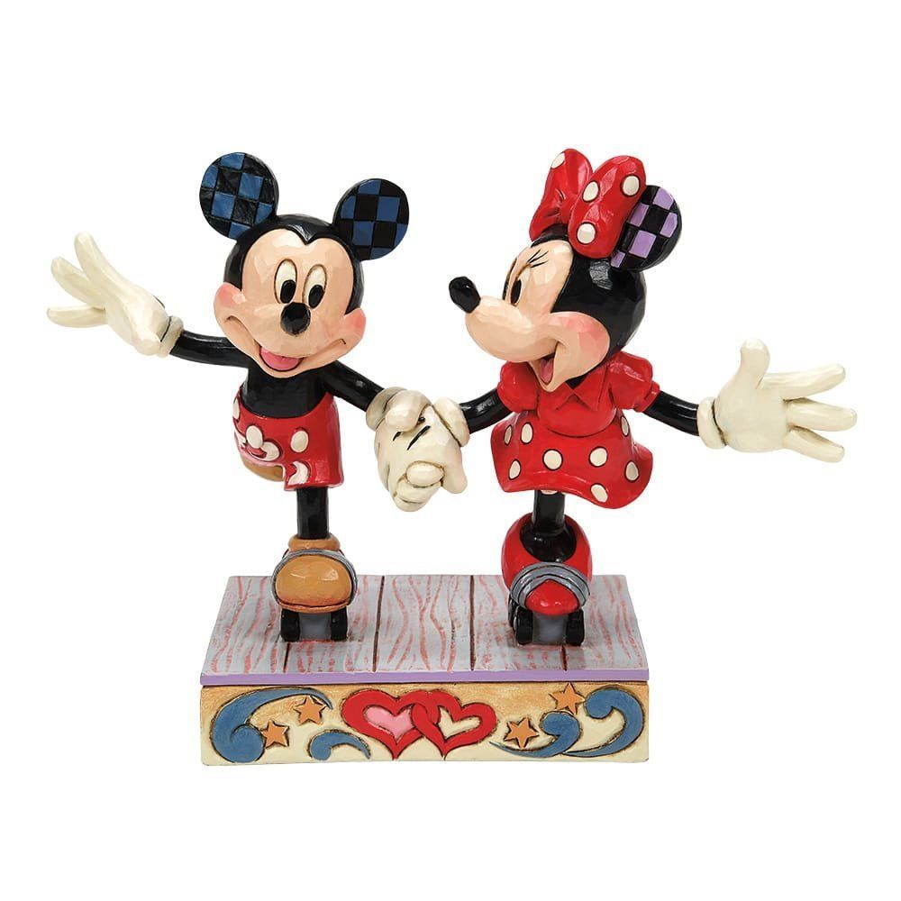 Mickey en Minnie Mouse-figuurtjes, hand in hand, in rode en zwarte outfits, staan op een sokkel met hartjes.