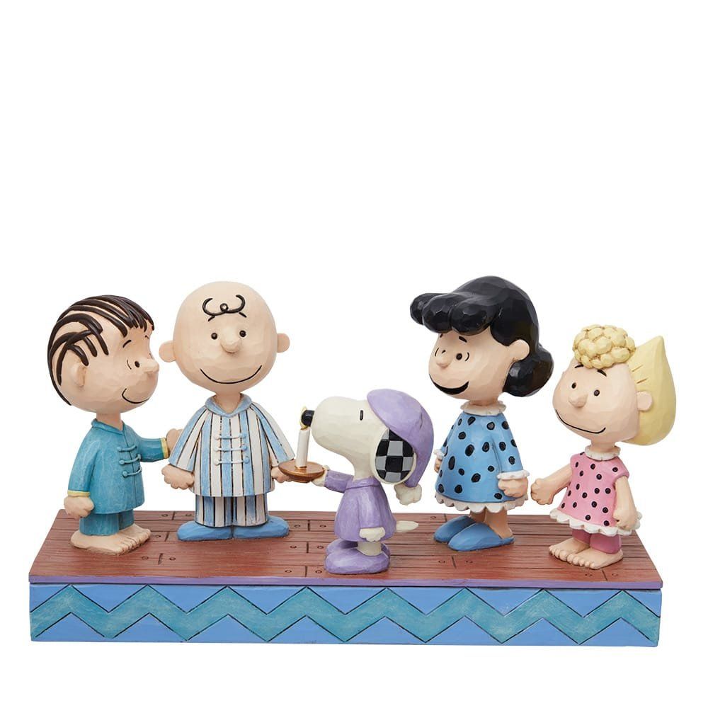 De Peanuts-figuren in pyjama's stonden bij elkaar, met Snoopy die een kaars vasthield.