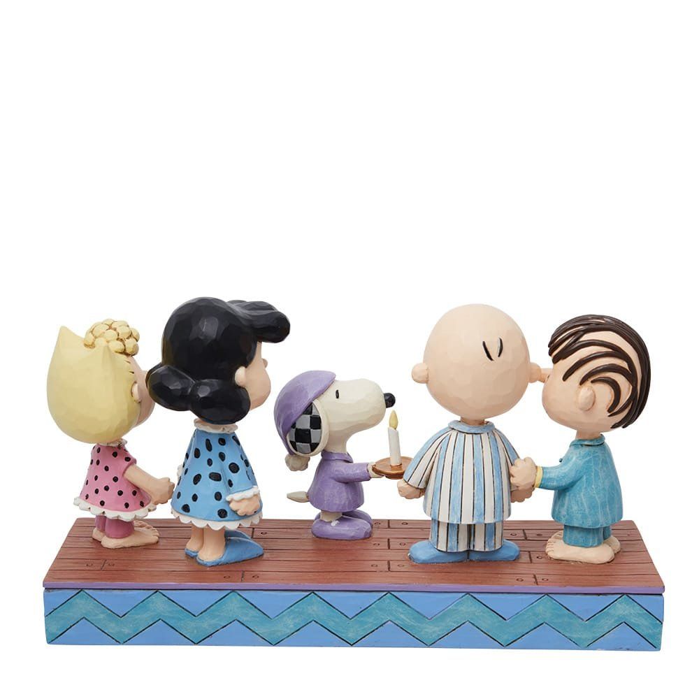 De Peanuts-figuren in pyjama's stonden bij elkaar, met Snoopy die een kaars vasthield.