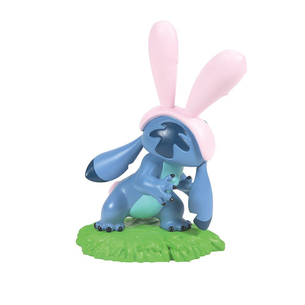 Een figuurtje van Stitch met konijnenoortjes, zittend op groen gras.