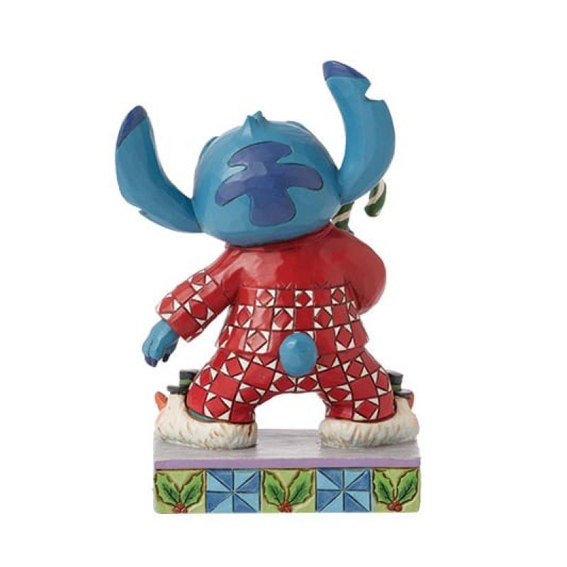 Een Stitch-figuurtje in een rode feestpyjama met een zuurstok, staand op een sokkel met patroon.