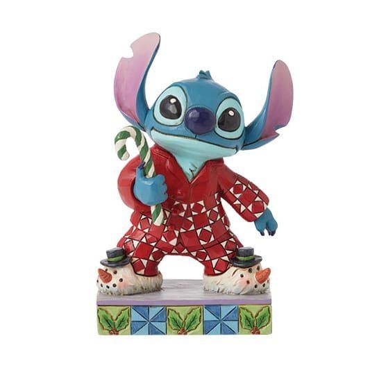 Een Stitch-figuurtje in een rode kerstpyjama met een zuurstok in zijn hand, staand op een sokkel versierd met een sneeuwpop.