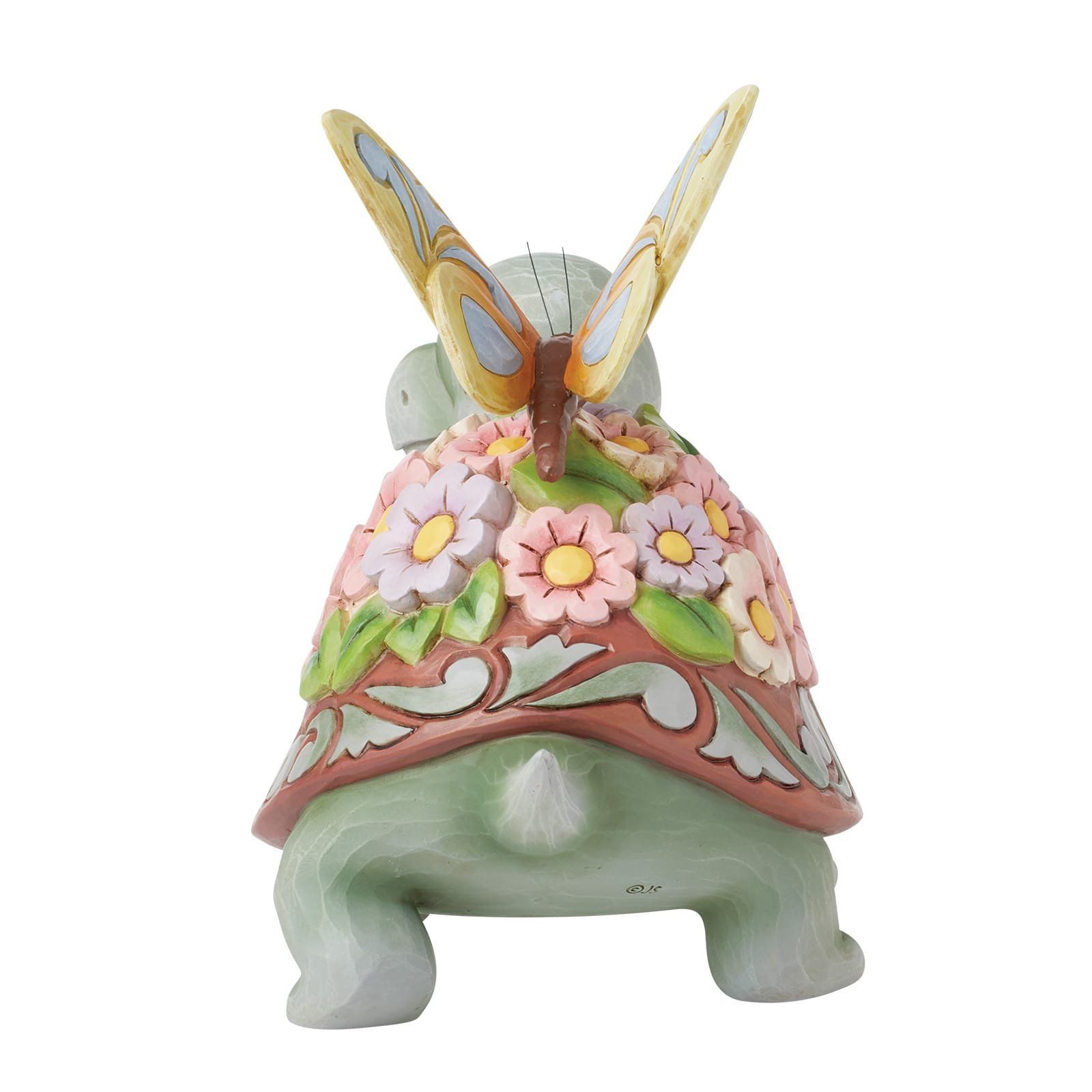 Groene schildpadfiguur met een bloemenmotief op het schild en een vlinder.