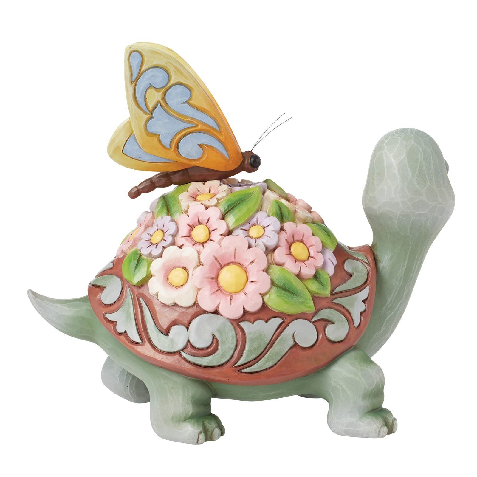 Een beeldje van een groene schildpad met een met bloemen bedekt schild en een gele vlinder erop.