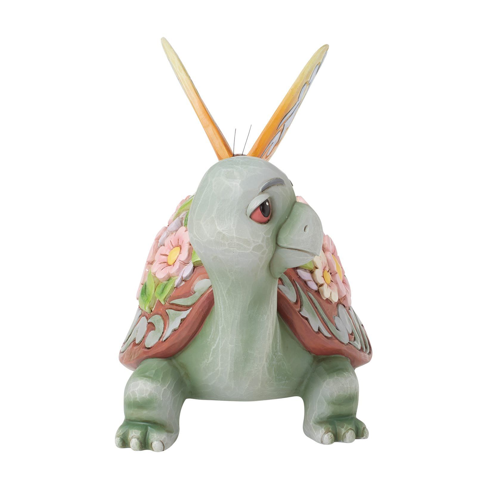 Groene schildpadfiguur met een schild vol bloemen en vlinderachtige voelsprieten.