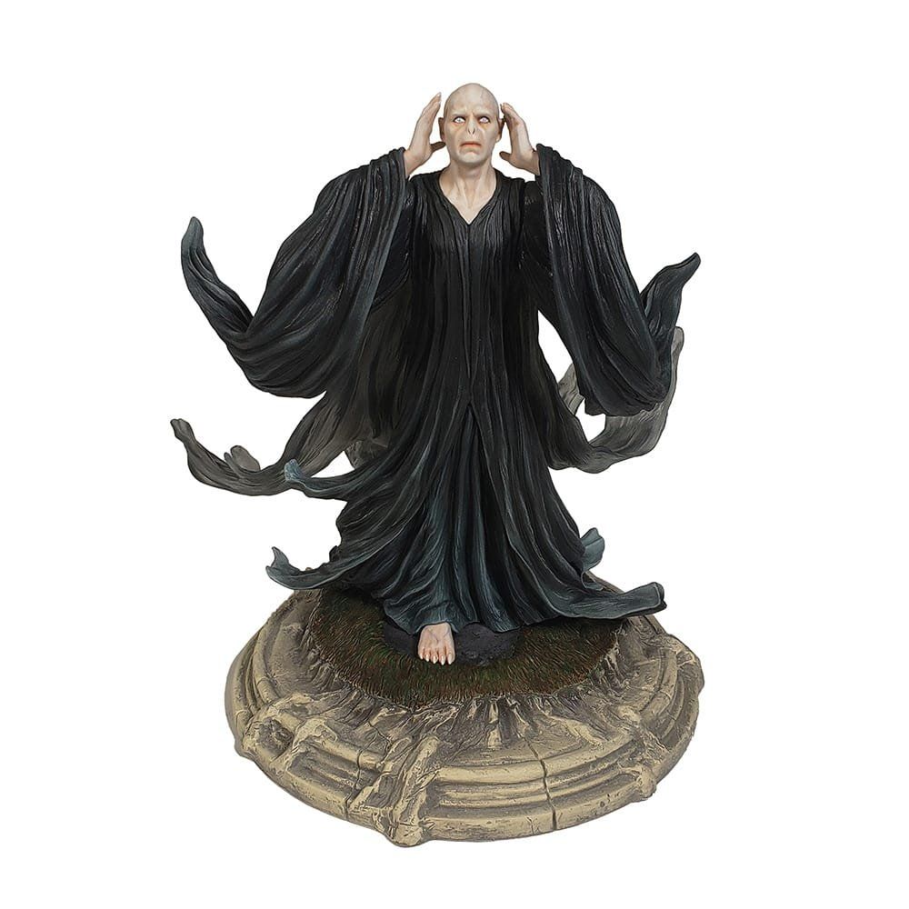 Beeldje van Heer Voldemort, kaal, met opgeheven armen, gekleed in zwarte gewaden, op een stenen sokkel.