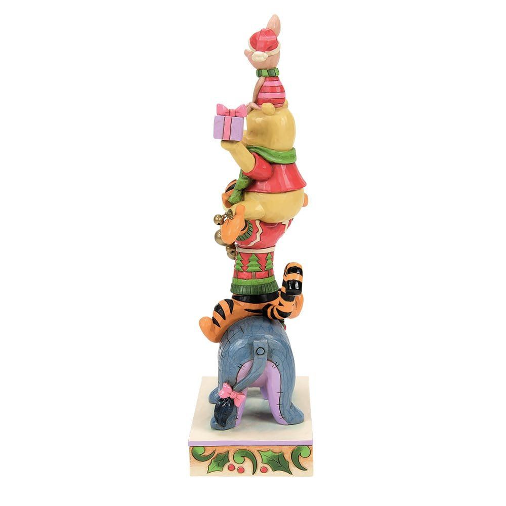 De personages van Winnie de Pooh opgestapeld: Knorretje bovenop, met een cadeautje in zijn hand, Pooh, Tijger en Iejoor onderaan. Kerstthema.