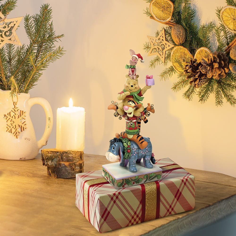 Een kerstfiguurtje van Winnie de Pooh met Knorretje, Iejoor en Tijger bovenop een cadeautje.