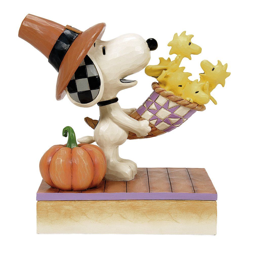 Snoopy met pelgrimshoed op, met een mandje vol Woodstock-vogels in zijn handen, naast een pompoen.