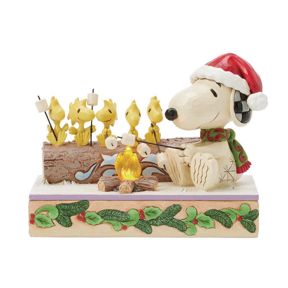 Snoopy, met een kerstmuts op, roostert marshmallows met Woodstock en zijn vrienden rond een kampvuur.