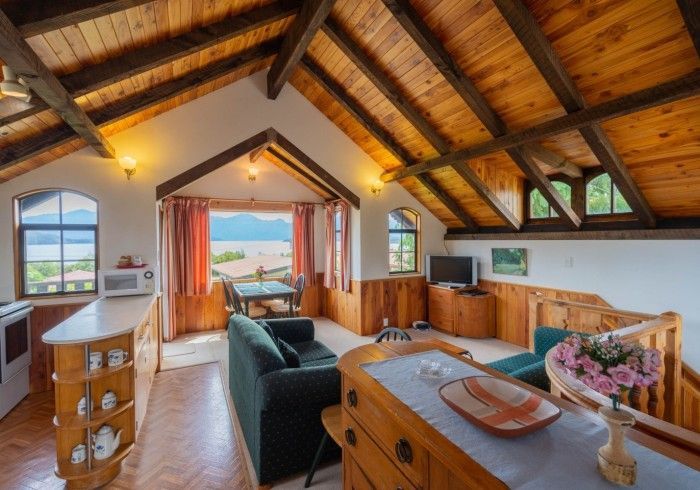 Cozy living space with wood ceiling and furniture. Includes a kitchen, sitting area, and view of the lake.