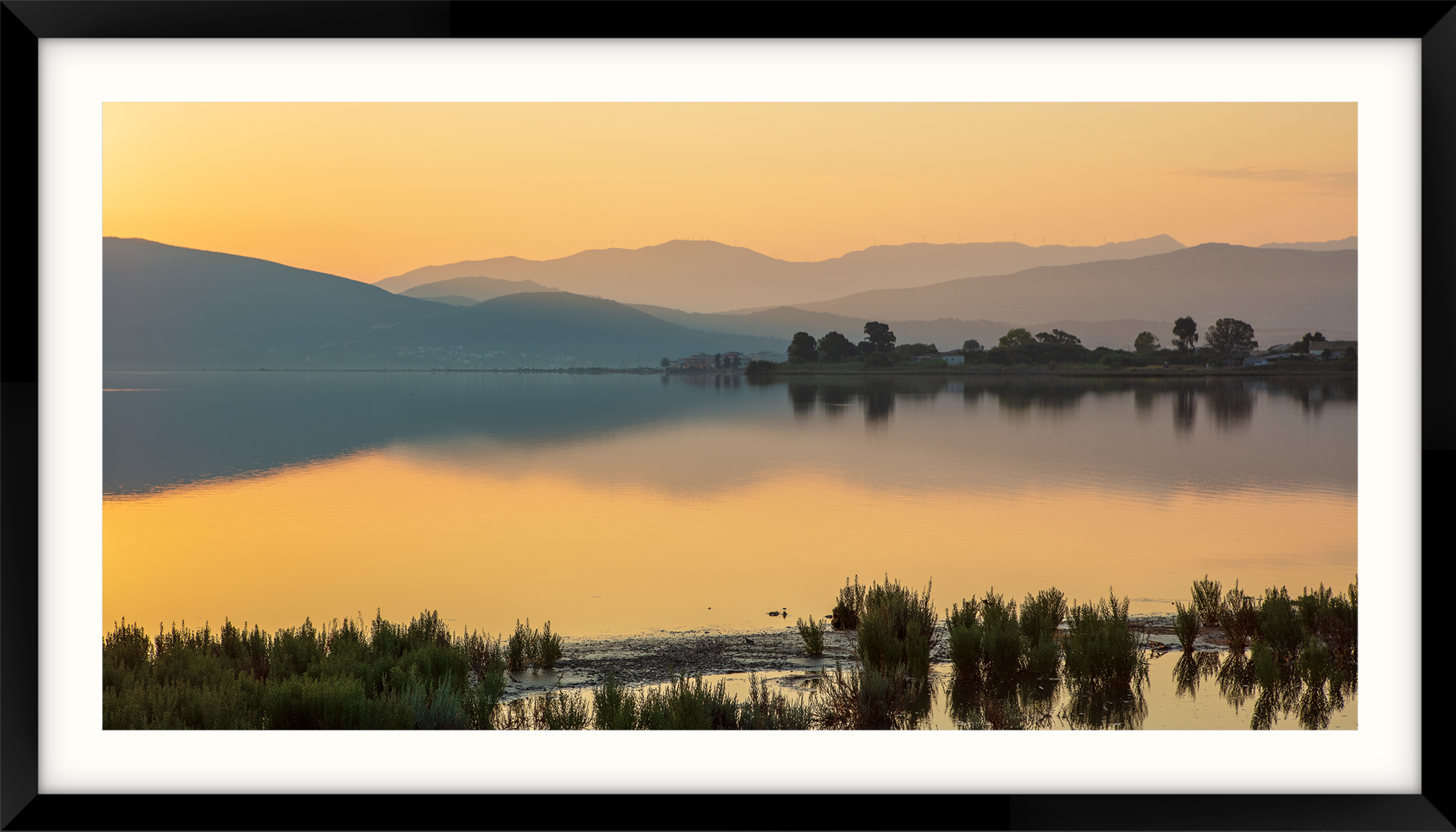a framed picture of a lake with mountains in the background