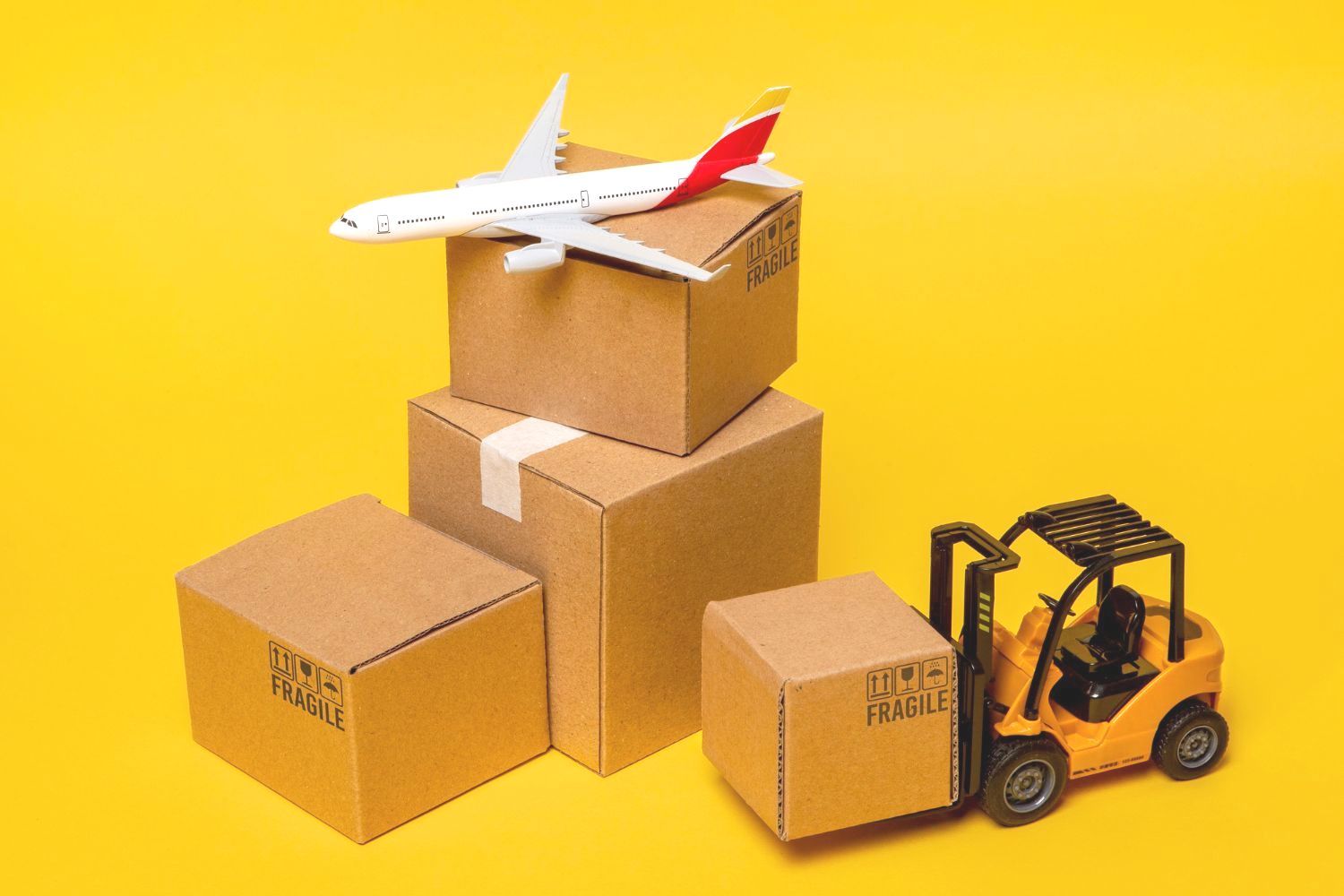 Un avión de juguete está sobre una pila de cajas de cartón al lado de una carretilla elevadora.