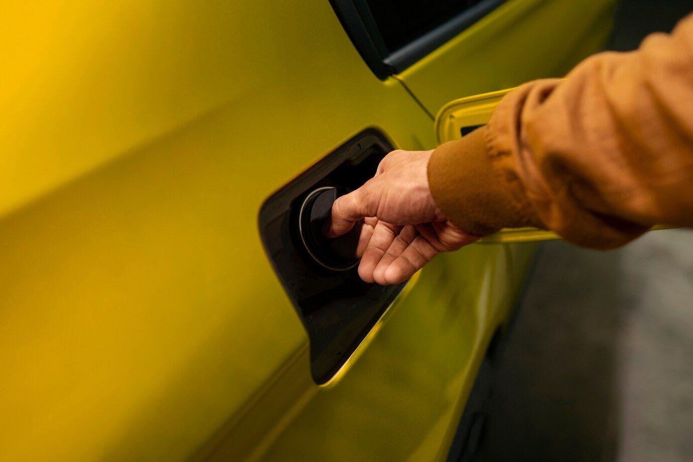 Una persona está echando gasolina a un coche amarillo.