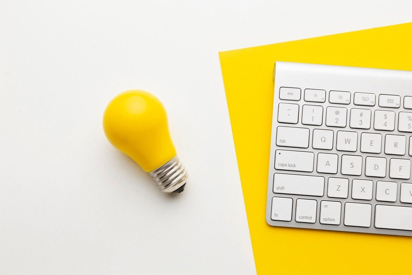 Una bombilla amarilla está al lado de un teclado blanco.