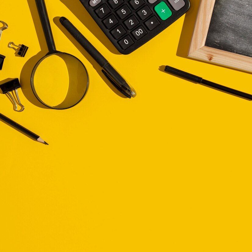 Sobre una mesa amarilla hay una calculadora, una lupa, un bolígrafo, clips para carpetas y una pizarra.