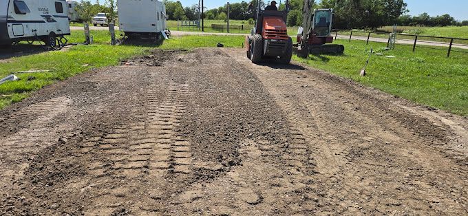 A man is driving a tractor down a dirt road.