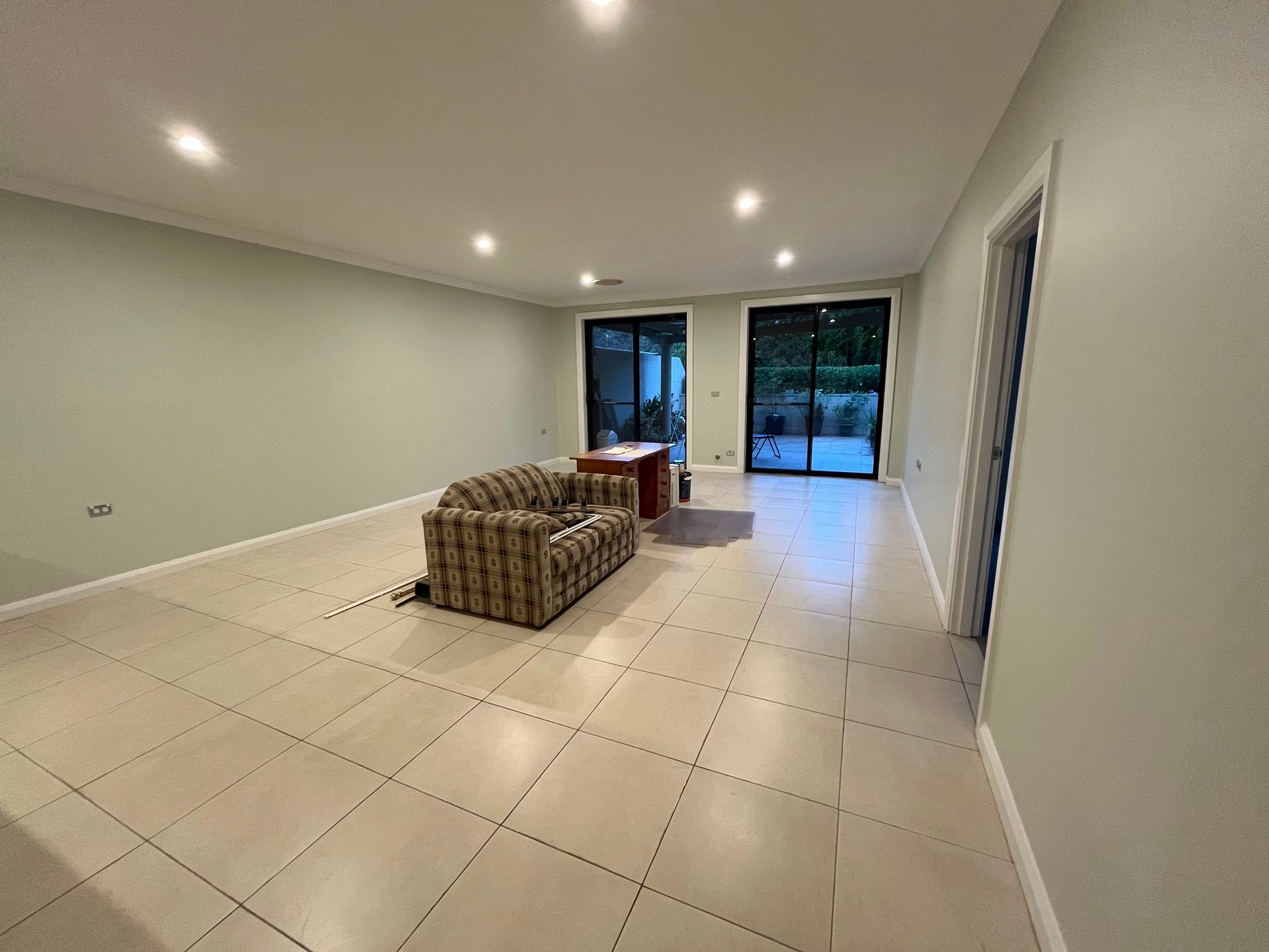 A spacious, bright room with light-colored tile floors, a patterned sofa in the center, and large glass sliding doors. A spacious, bright room with light-colored tile floors, a patterned sofa in the center, and large glass sliding doors.