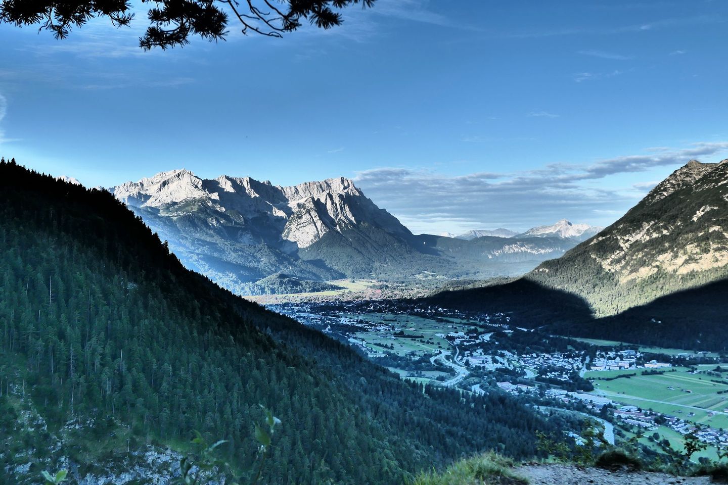 Green mountain valleyin Bavaria  overlooking a sunlit town and green fields under a clear blue sky