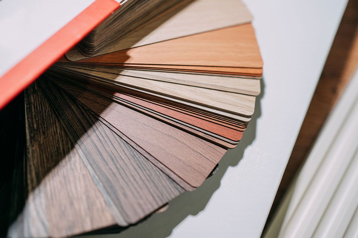 Color swatch fan, primarily wood tones, fanned out on white surface, with partial view of a paint roller. Color swatch fan, primarily wood tones, fanned out on white surface, with partial view of a paint roller.