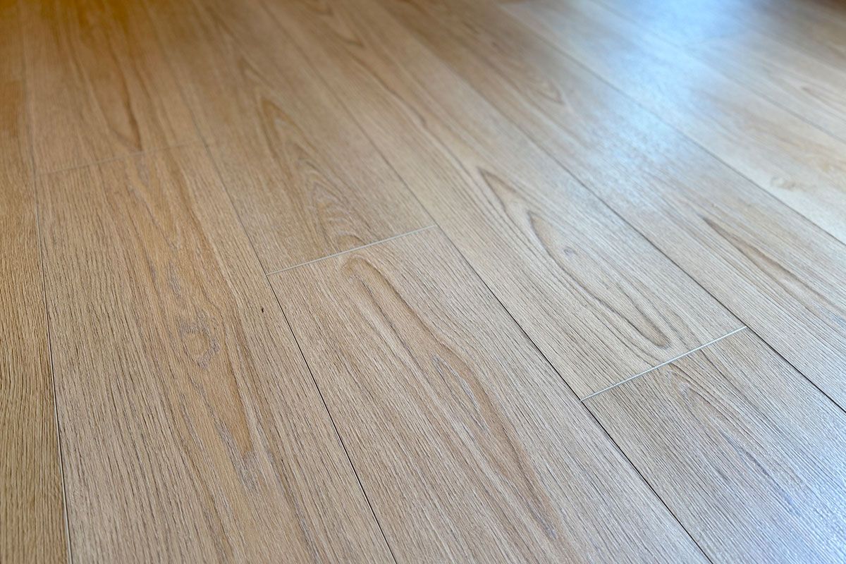 Close-up of light-colored wooden floorboards, with subtle grain patterns and visible seams. Close-up of light-colored wooden floorboards, with subtle grain patterns and visible seams.