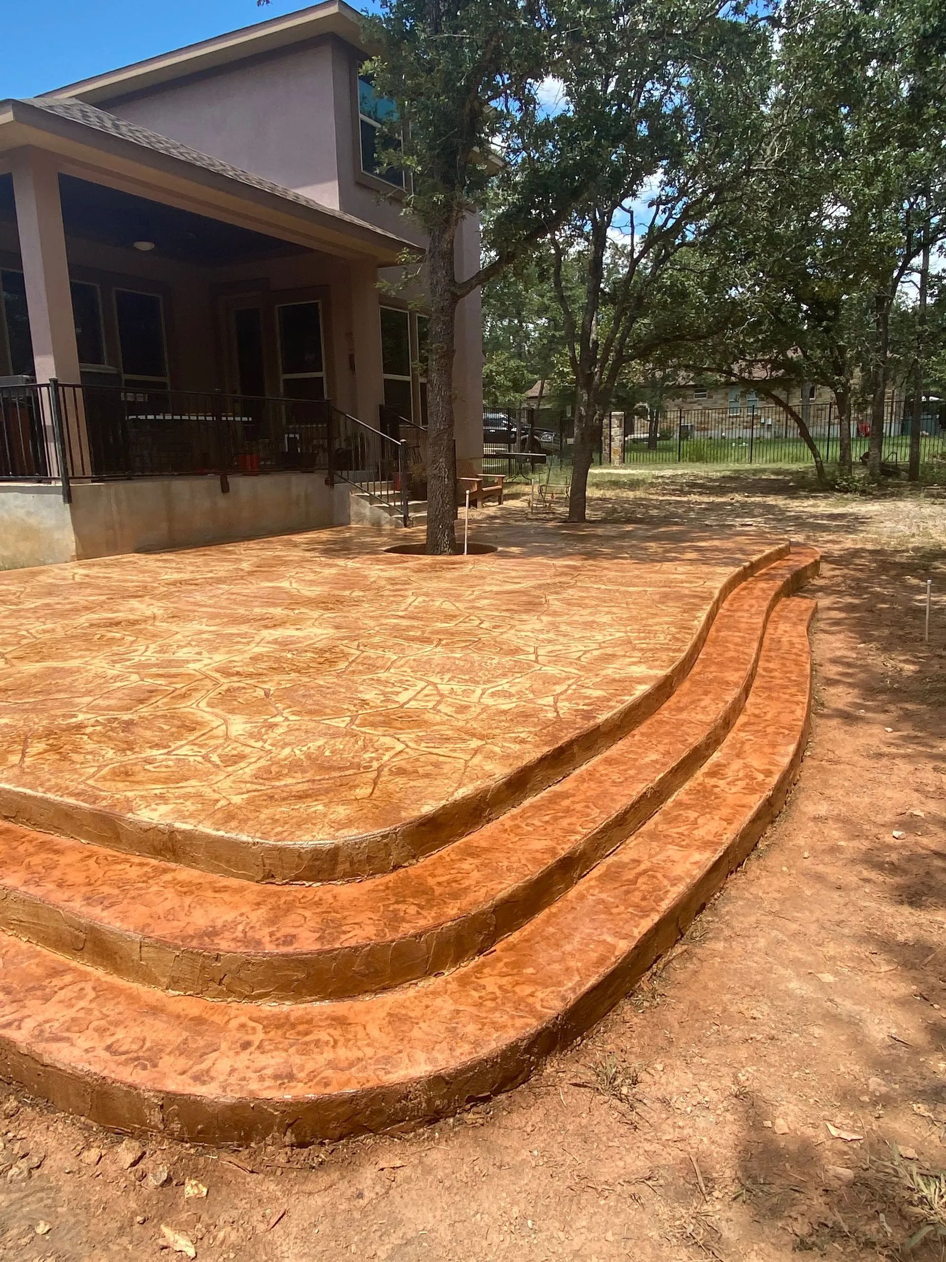 Red brick stepped seating in a dirt yard beside a house and trees