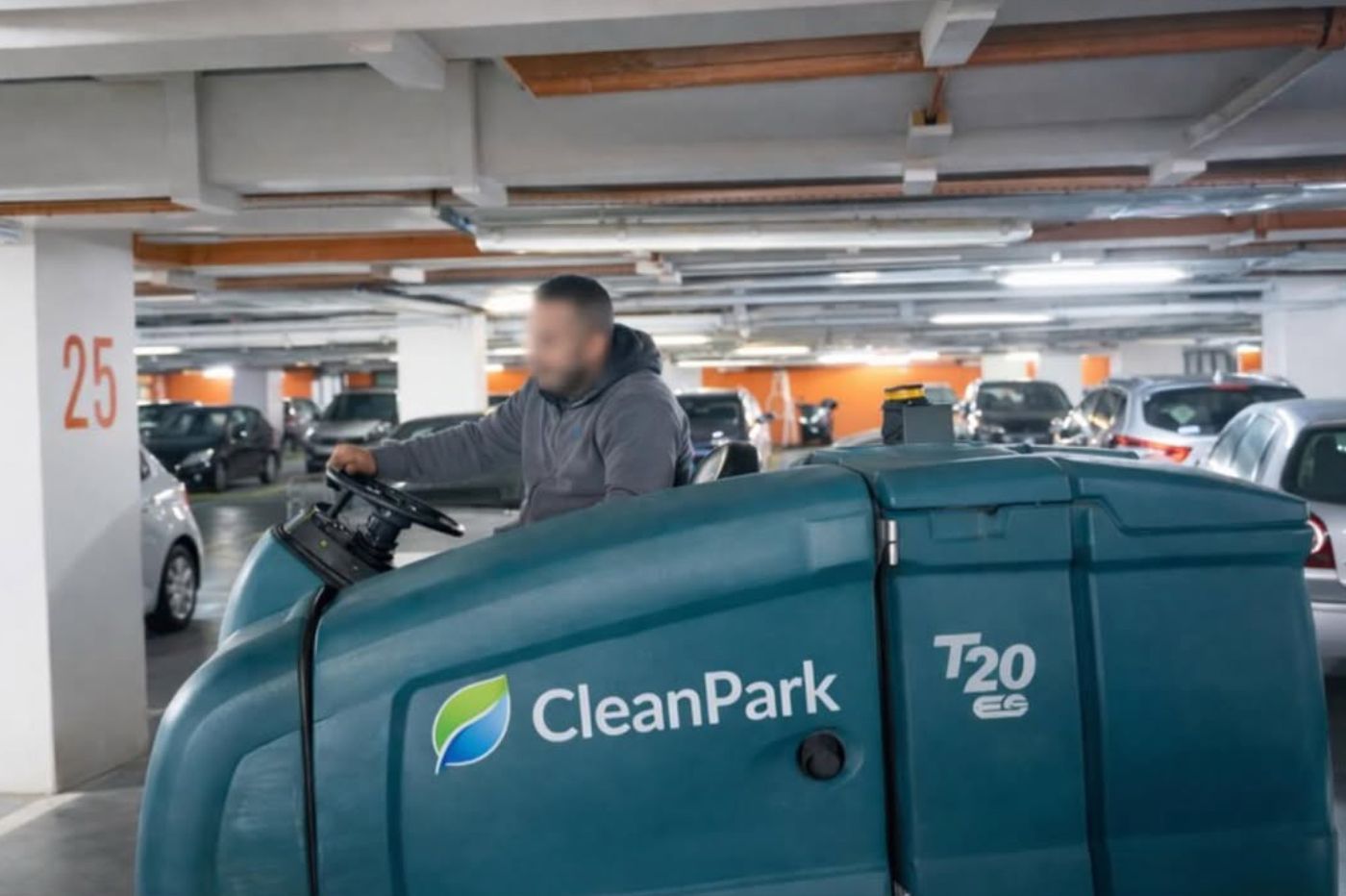 Une personne se trouve sur une autolaveuse CleanPark T20 dans un parking souterrain.
