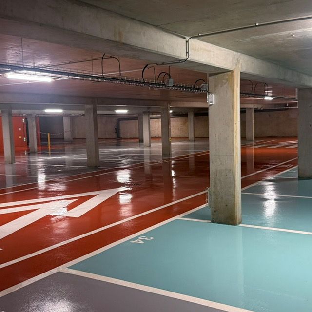 Parking souterrain vide avec des voies peintes en rouge, blanc et bleu clair et des piliers en béton