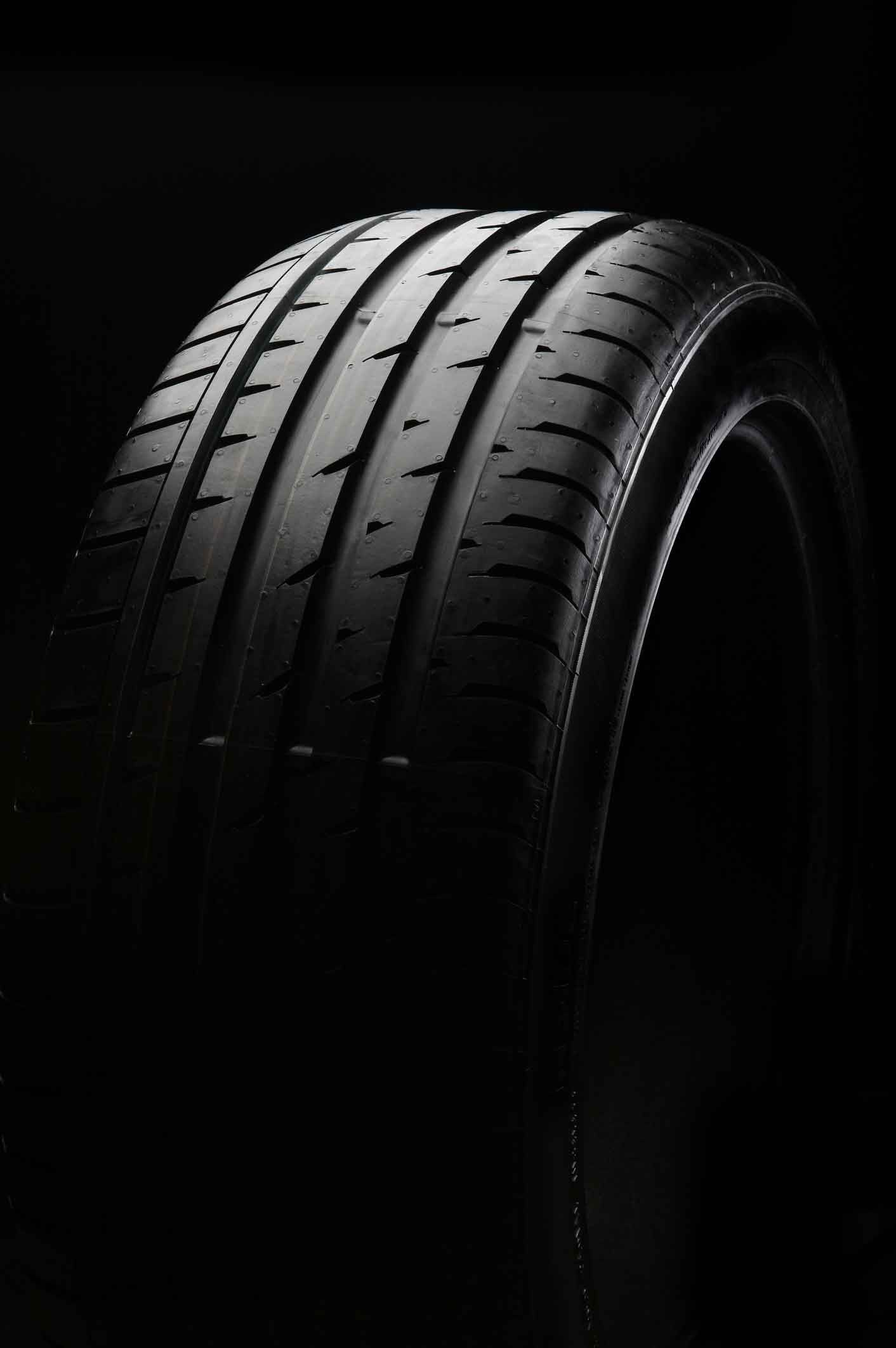 A close up of a car tire on a black background.