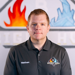 Headshot of a man in a black polo shirt standing before a blurred fire and ice logo backdrop