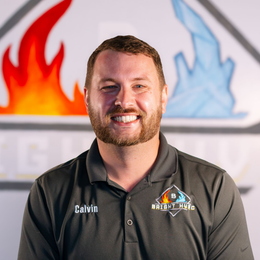 Smiling man in a dark polo shirt with a fire-and-ice logo, standing before a fire and ice backdrop