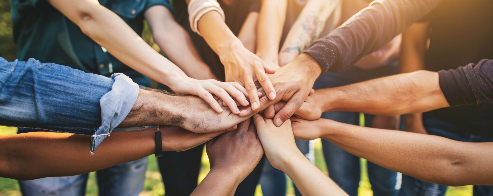 A group of people are putting their hands together in a circle.