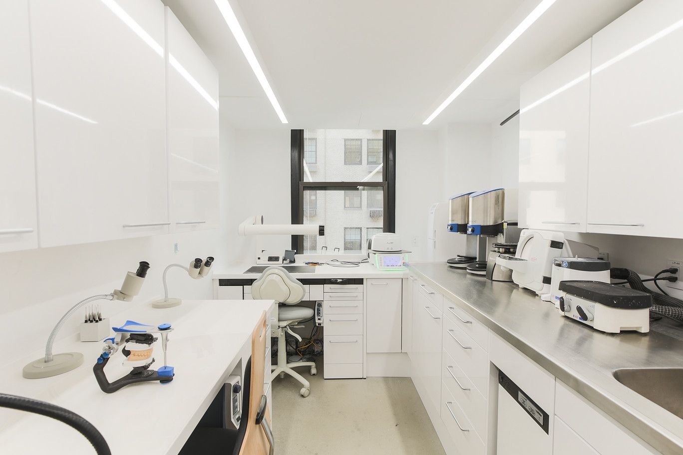 Bright modern dental clinic with white cabinets, treatment chairs, and dental equipment