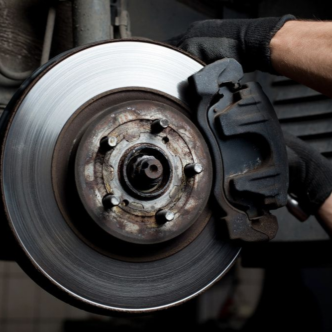 Car Brake Rotor and Caliper Being Inspected by a Gloved Hand — Alice Springs Auto Parts in Ciccone, NT