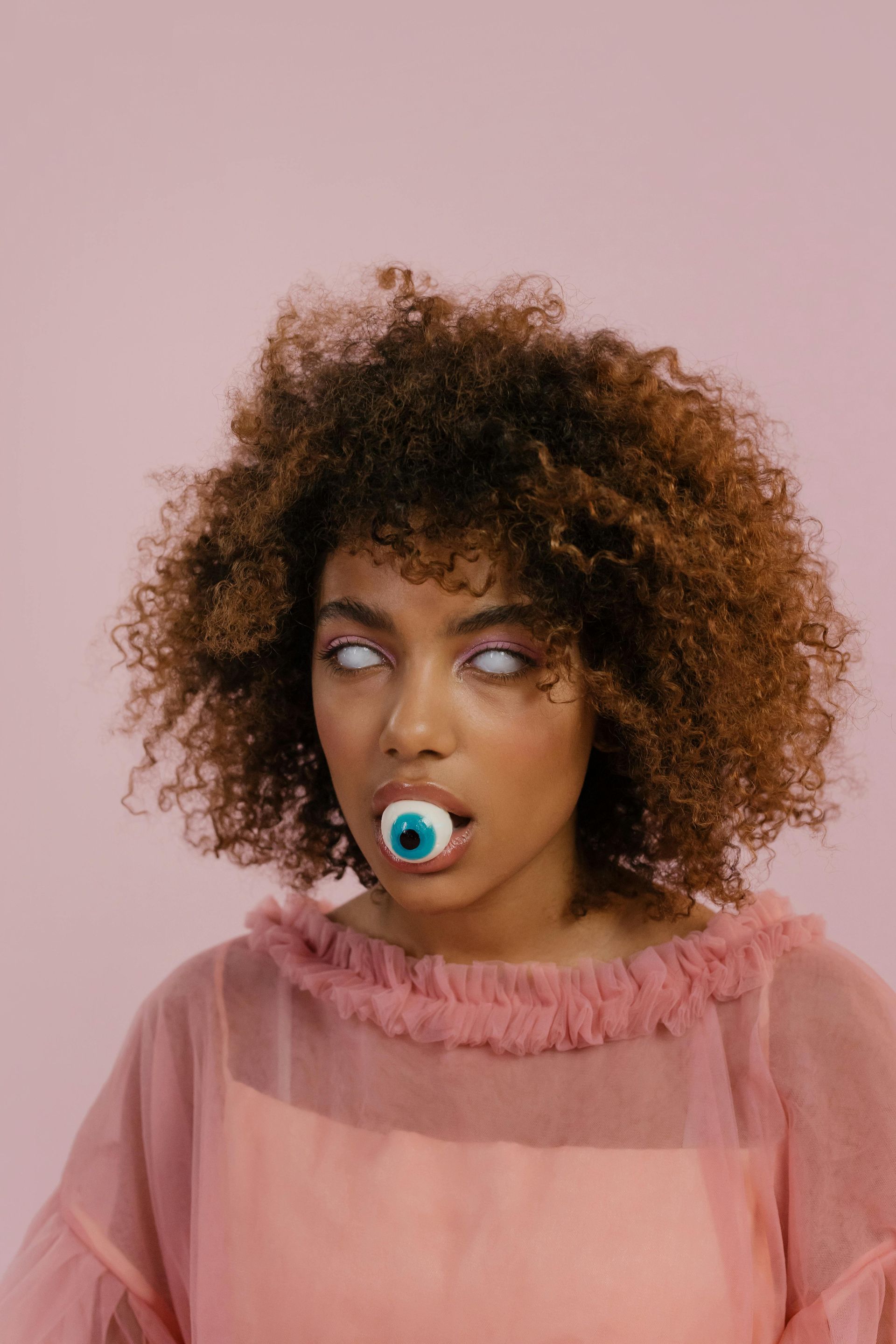 A woman with white eyes and a blue eye in her mouth.