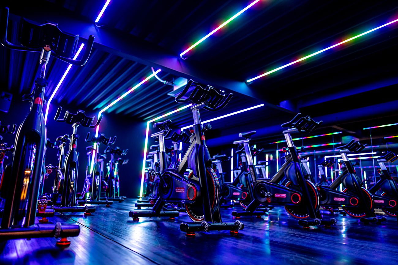 Spinninglesstudio, binnen met hometrainers en neonverlichting in de kleuren blauw, groen en rood.