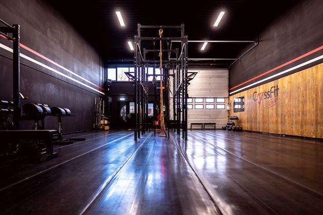 Interieur van een sportschool met fitnessapparatuur, zwarte muren en houten accenten.
