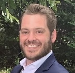A man in a suit and tie is smiling for the camera.