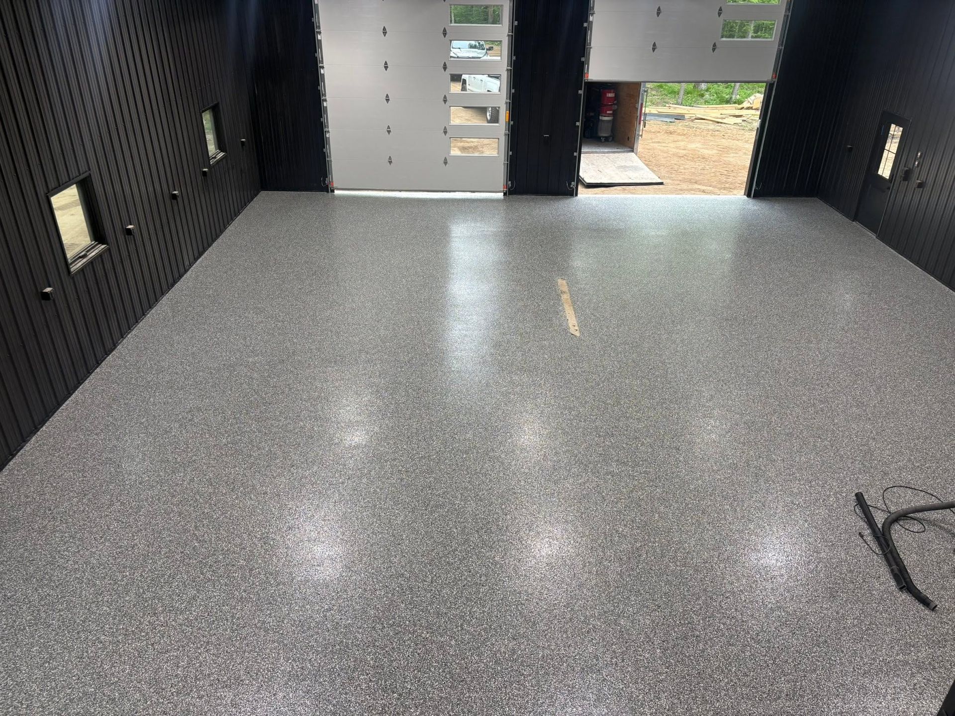 Empty black-walled van interior with a speckled gray floor and open rear doors.