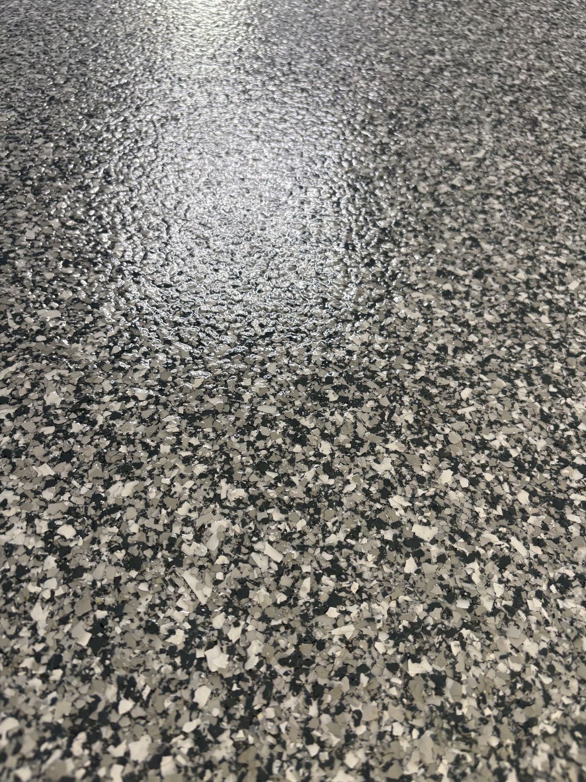 Close-up of speckled gray terrazzo floor with a bright reflection near the center