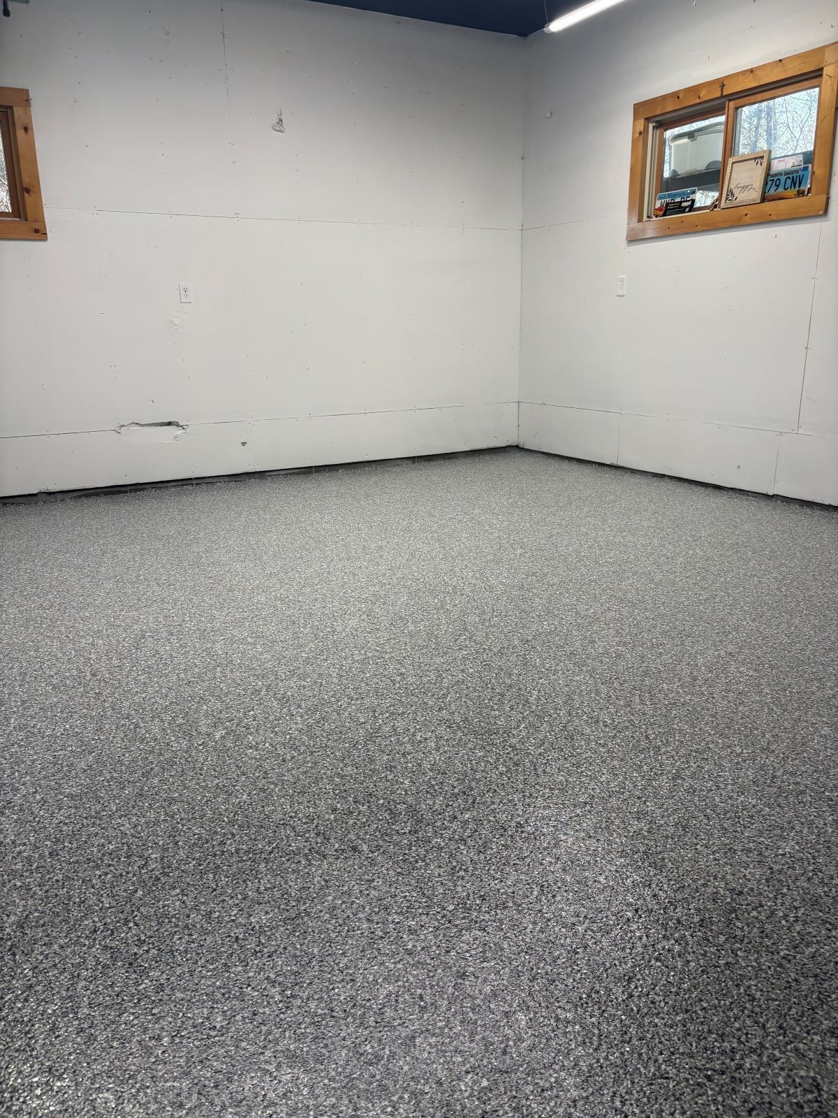 Empty room with white walls, small windows, and speckled gray carpet.