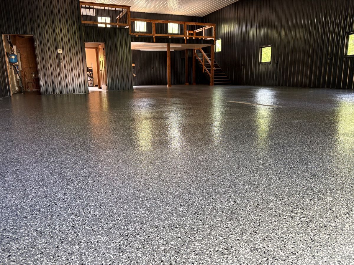 Empty indoor hall with a polished speckled floor, dark wood walls, and a loft balcony in the background