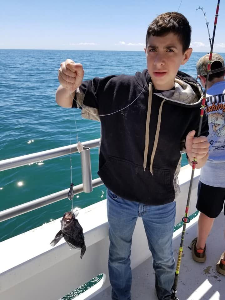 Person on a boat holding a fishing rod and catch over the blue ocean