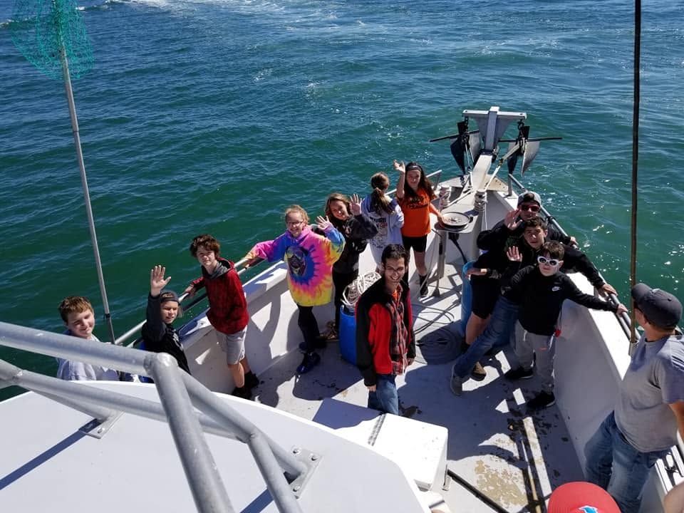 People posing on a boat deck with ocean water in the background